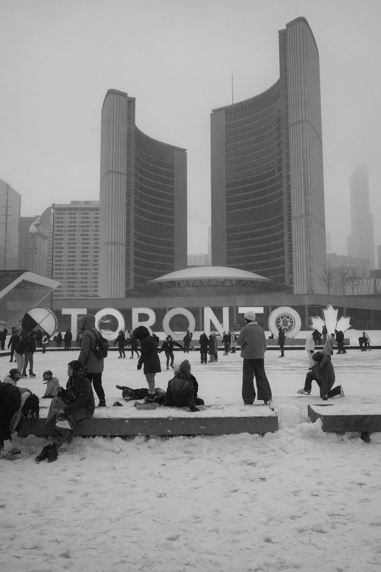 Skaters beneath Toronto City Hall in the snow