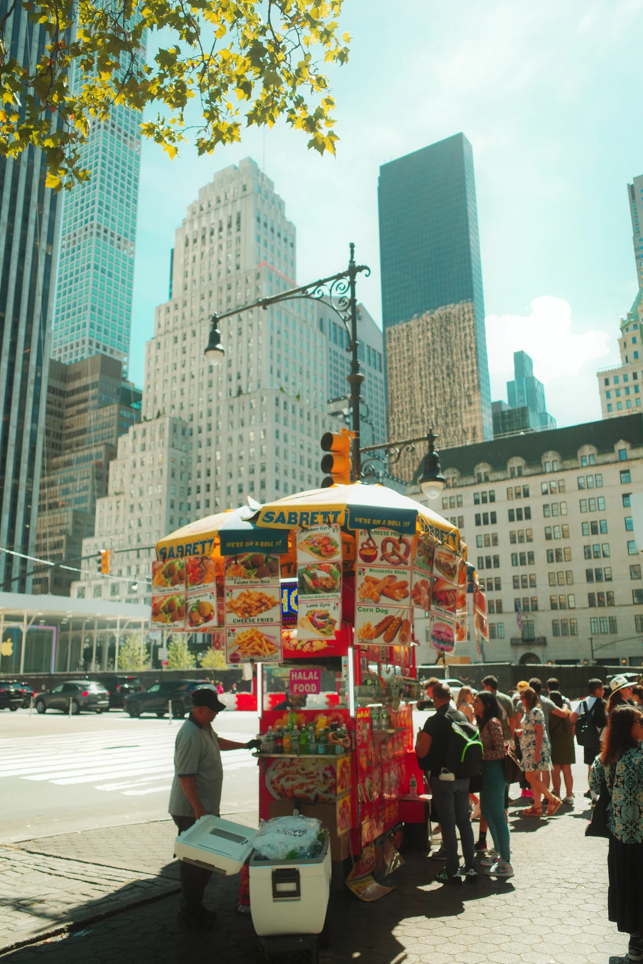 A food cart and a queue beneath Manhattan towers