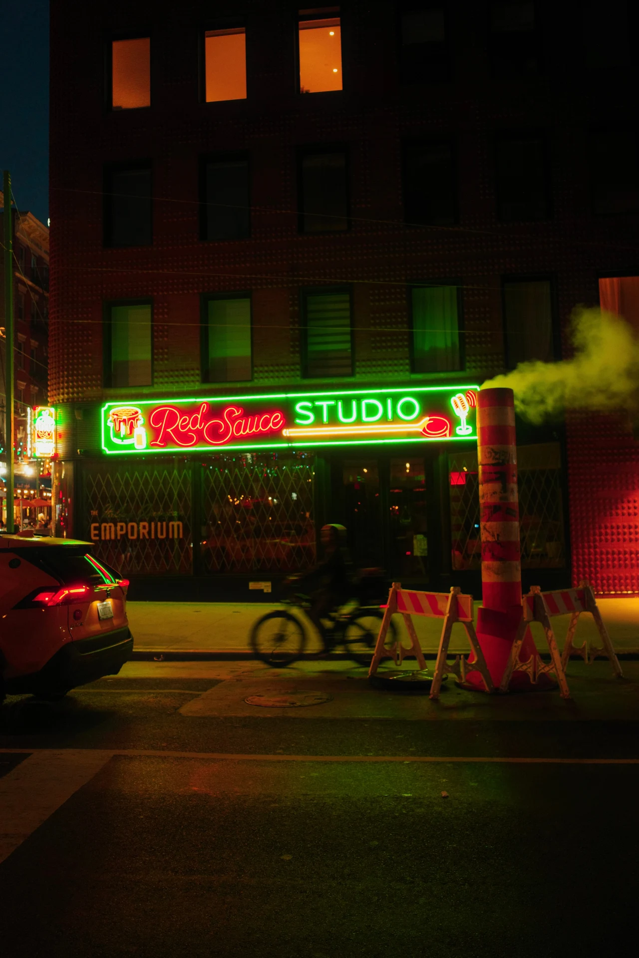A cyclist passing green and red neon after dark